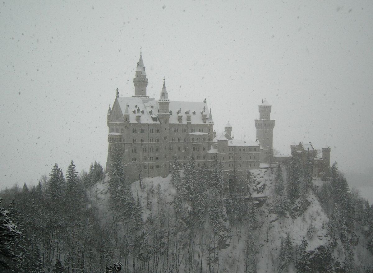 Schloss Neuschwanstein bei Schneefall über dem verschneiten Wald